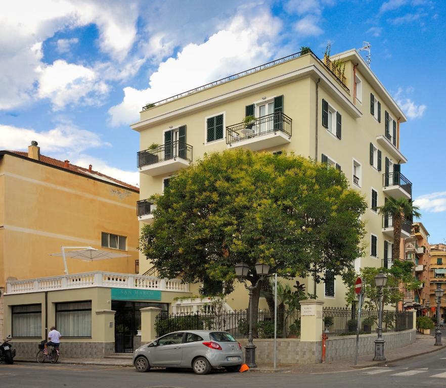 a white building with a car parked in front of it at Residence San Marco Suites&Apartments Alassio in Alassio