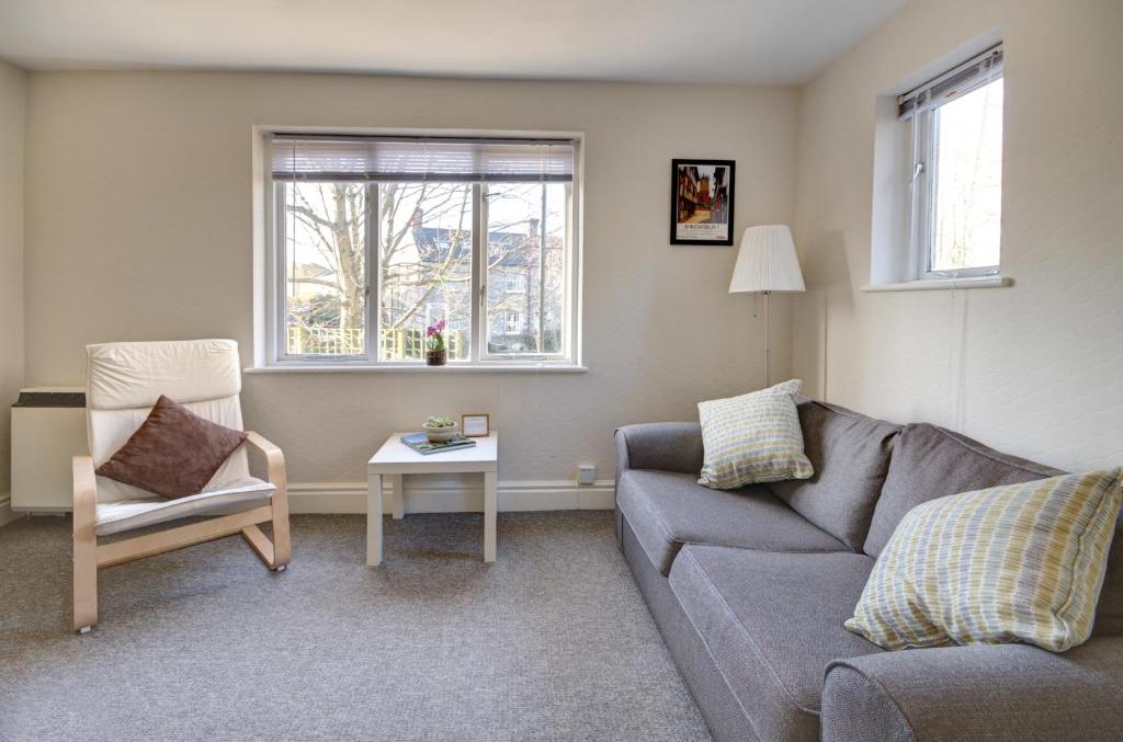 a living room with a couch and a chair at Bridge House By Treetop Property in Cirencester