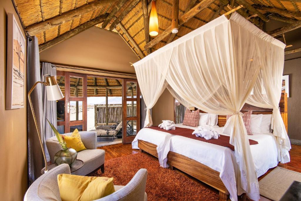 ein Schlafzimmer mit einem großen Bett mit Baldachin in der Unterkunft Hoodia Desert Lodge in Sesriem