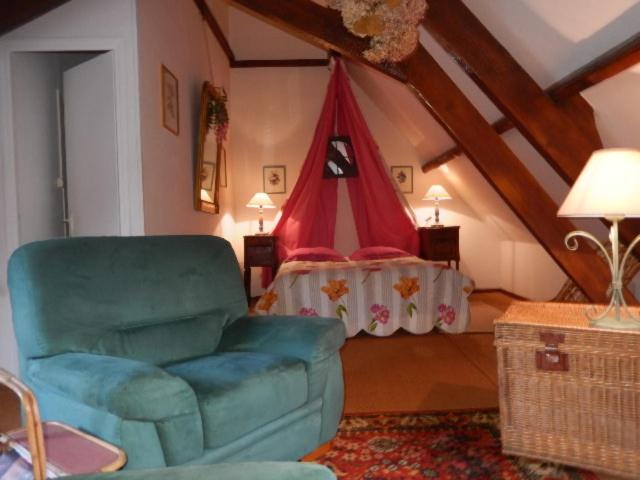 ein Wohnzimmer mit einem Stuhl und einem Bett in der Unterkunft Chambres d'hôtes ''La Grand' Maison'' in Escalles