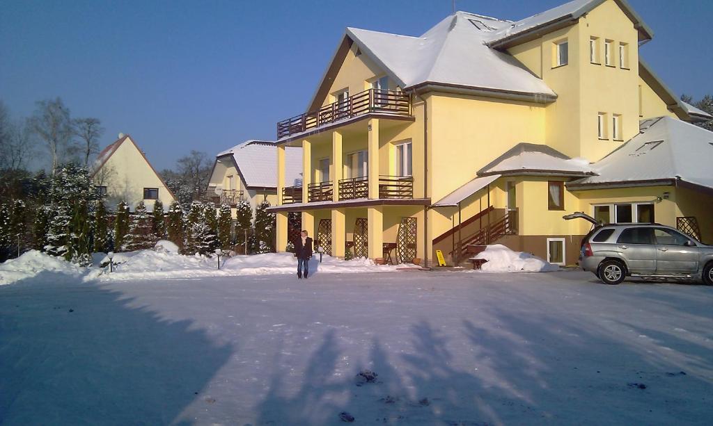 een persoon die voor een huis in de sneeuw staat bij Willa Rosa in Kajetany