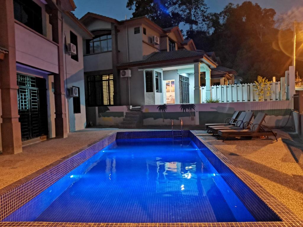 a swimming pool in front of a house at night at Fuxi fruit garden villa Langkawi 富囍休闲度假水果园别墅兰卡威 in Kuah