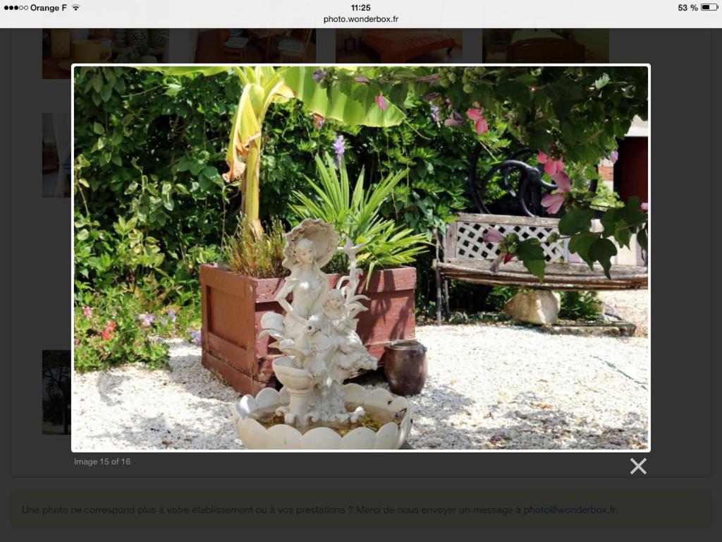 una statua in un giardino con panchina e piante di Chambres et table d'hôtes les grivottes a Boulleret