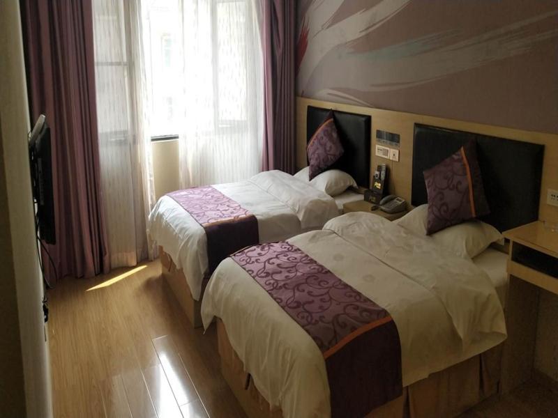 een hotelkamer met 2 bedden en een raam bij Thank Inn Chain Hotel guizhou south prefecture longli county high-speed railway station in Longli