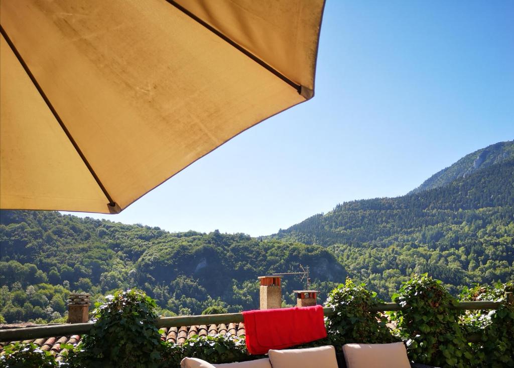 uma mesa e cadeiras numa varanda com montanhas ao fundo em la maison sous le château em Montségur