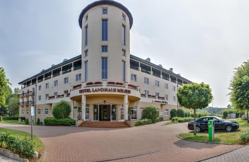 ein großes weißes Gebäude mit einem davor geparkt in der Unterkunft Hotel Landhaus Milser in Duisburg