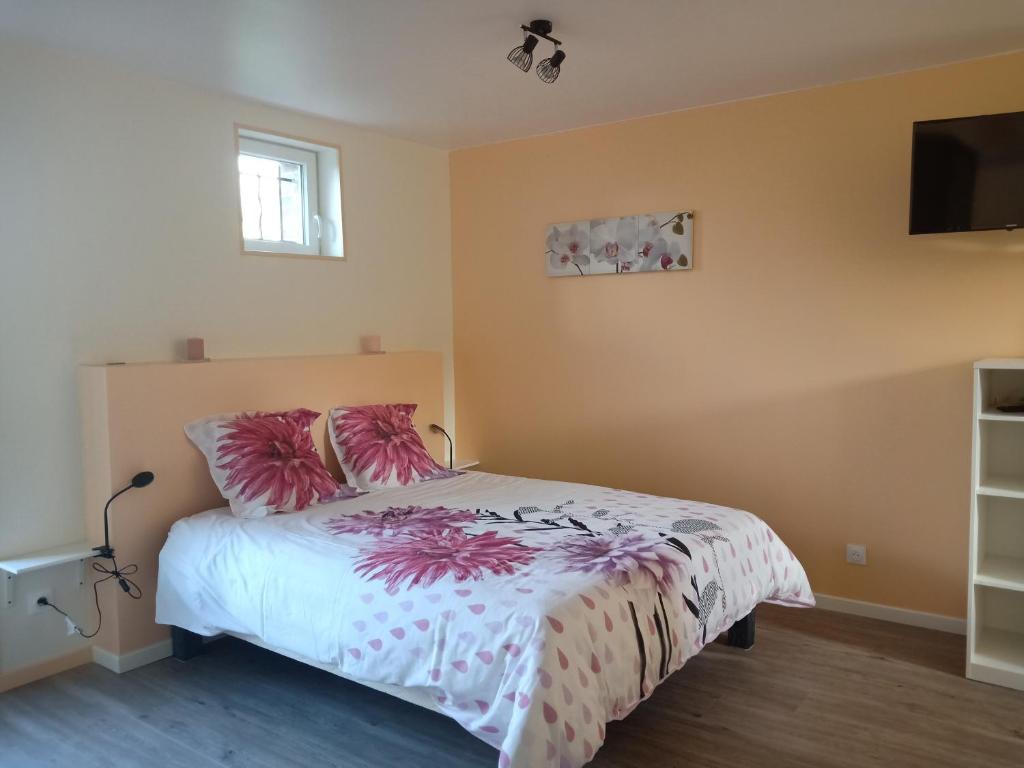 a bedroom with a bed with pink pillows and a tv at Chez Magali in Courtemaux