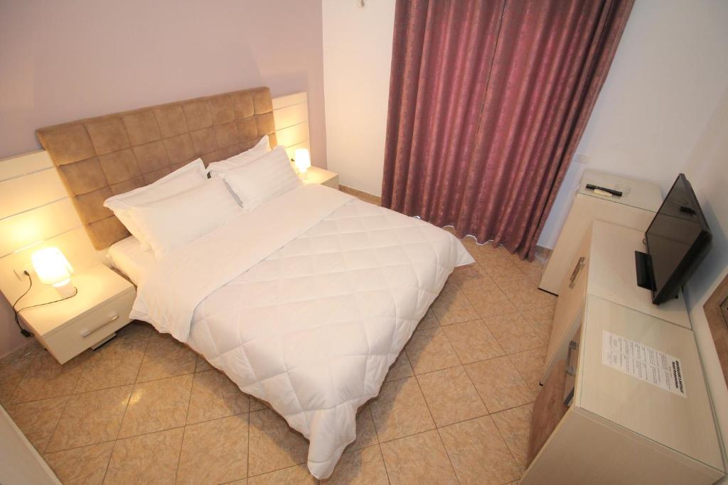 a bedroom with a large bed and a television at Julia Hotel in Sarandë