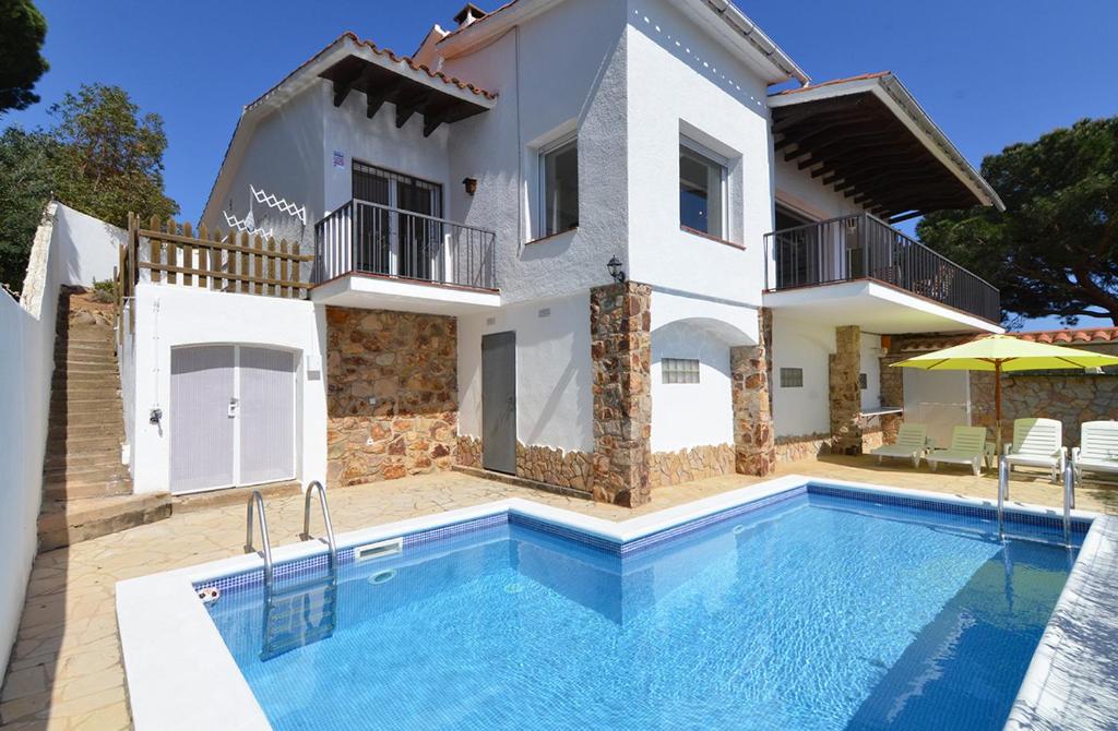 eine Villa mit einem Pool vor einem Haus in der Unterkunft Club Villamar - Pitagoras in Lloret de Mar