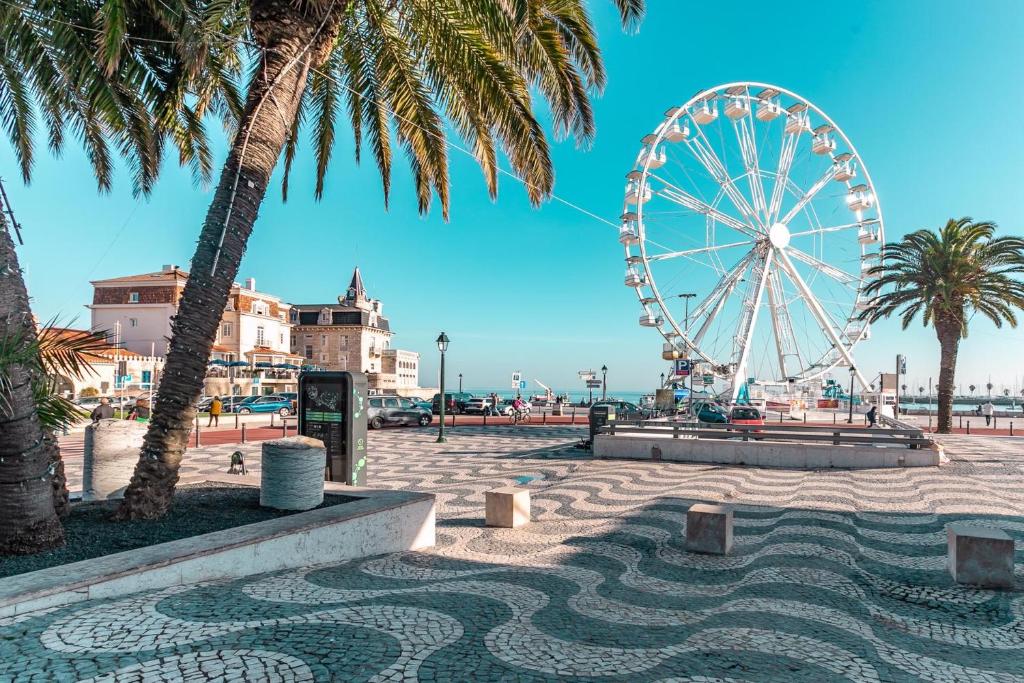 une roue ferris sur une plage bordée de palmiers dans l'établissement Wine Inn Cascais Guesthouse, à Cascais