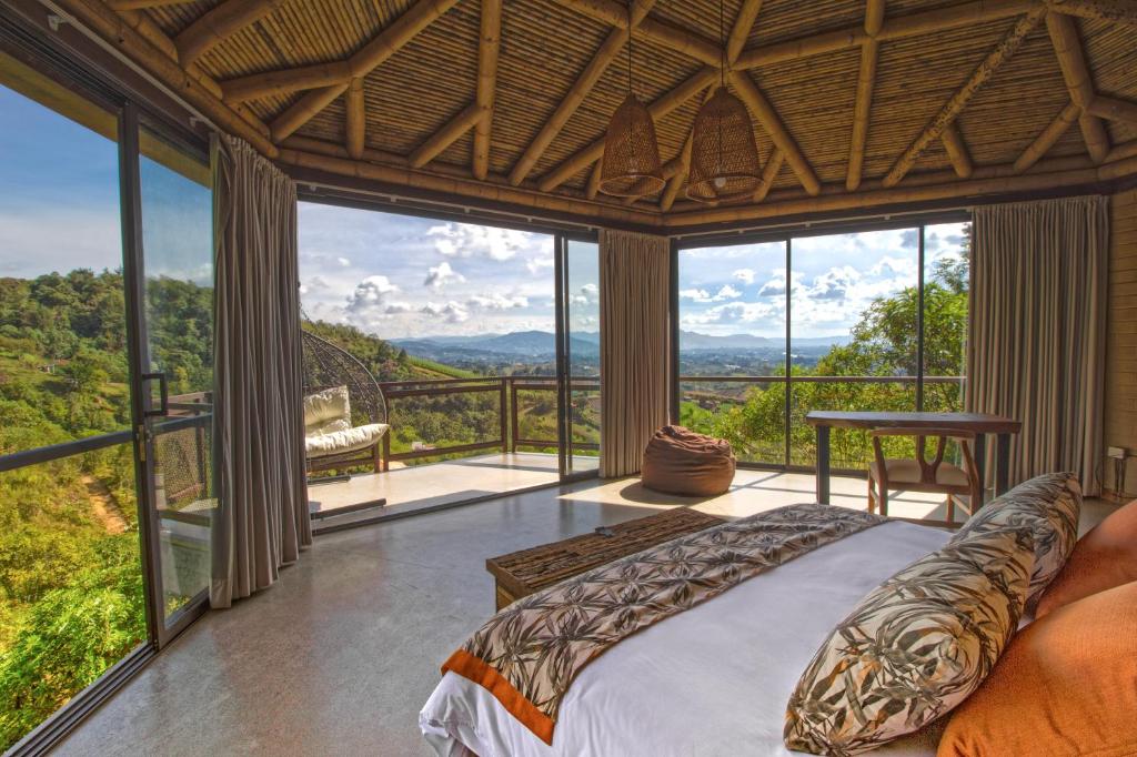 a bedroom with a bed and large glass windows at Cannua Lodge in Marinilla