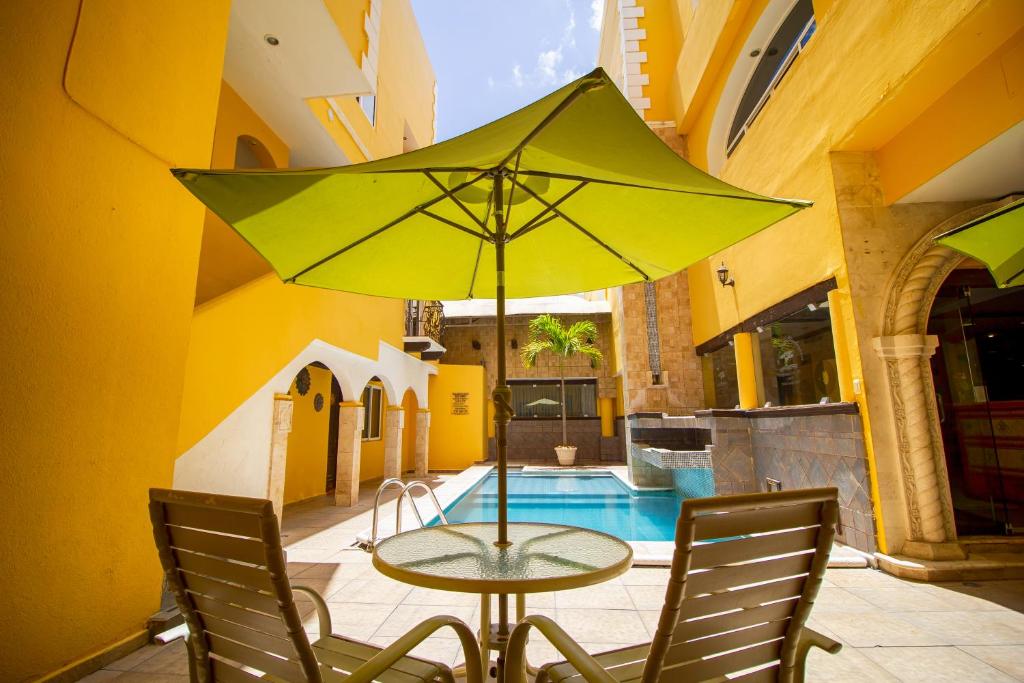 a table with a yellow umbrella in a courtyard at Suites Flamboyanes in Mérida