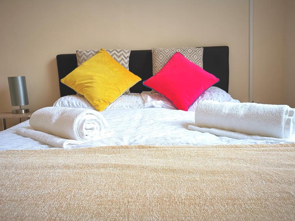 a bed with three colorful pillows on it at J BOOK NOW, Spacious 5 Bed Sleeps 9 Long Stays Workers & Families by Your Night Inn Group in Wolverhampton