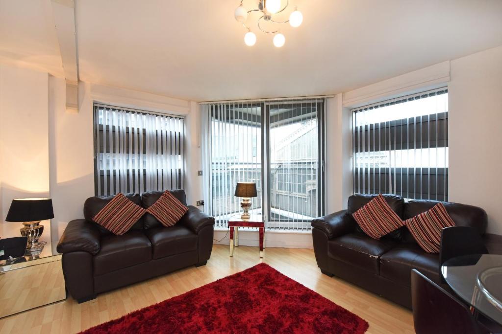 a living room with two leather couches and a red rug at Dreamhouse Apartments Manchester City Centre in Manchester