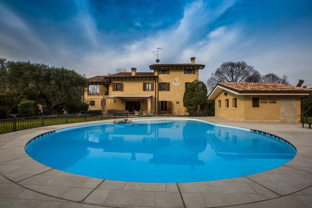 a large blue swimming pool in front of a house at Casale la Meridiana in Ponti Sul Mincio