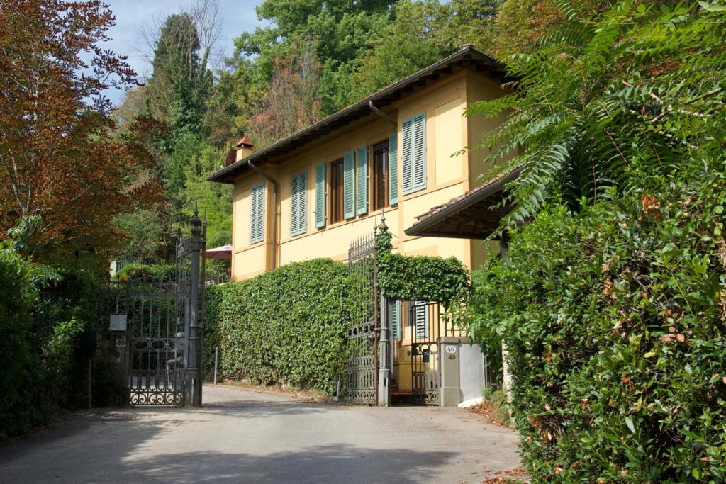 una casa gialla con un cancello di fronte a un vialetto di Villa Porta Romana - Family country house in the heart of Florence a Firenze