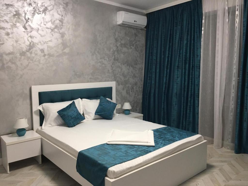 a bedroom with a white bed with blue pillows at Villa George in Constanţa