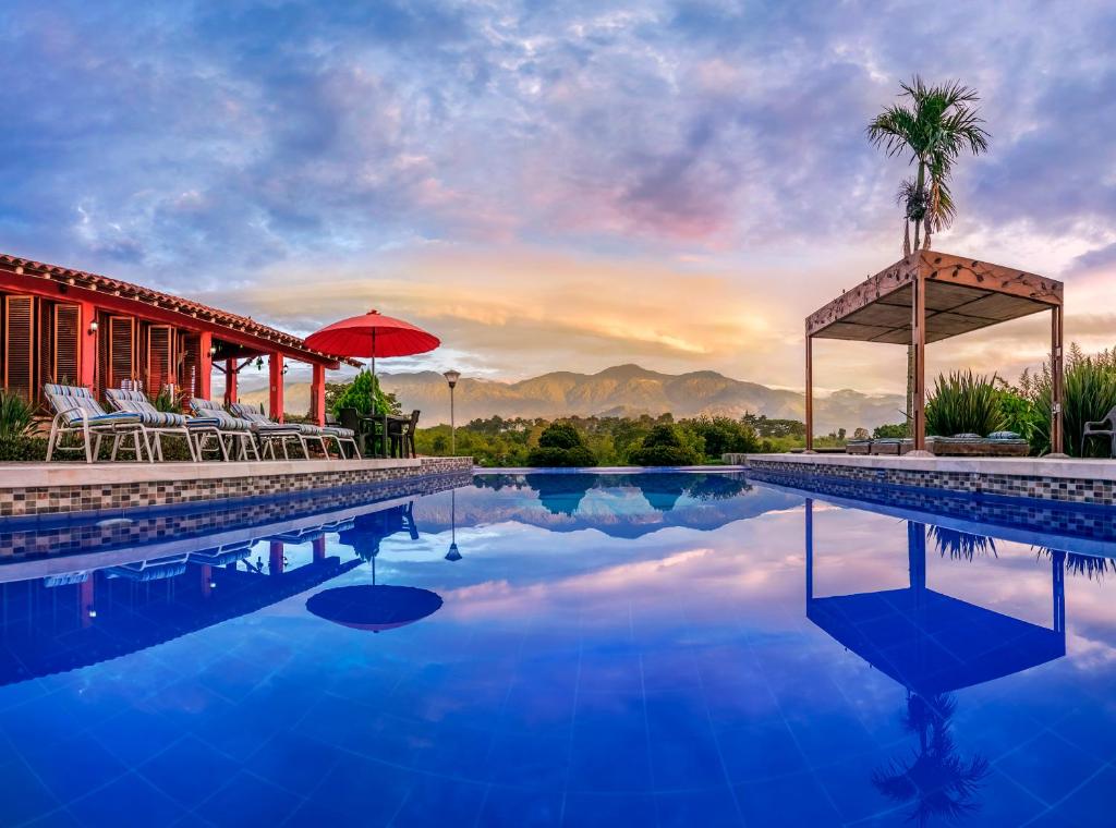 a resort swimming pool with a sunset in the background at Hotel Campestre Solar De La Luna in Armenia