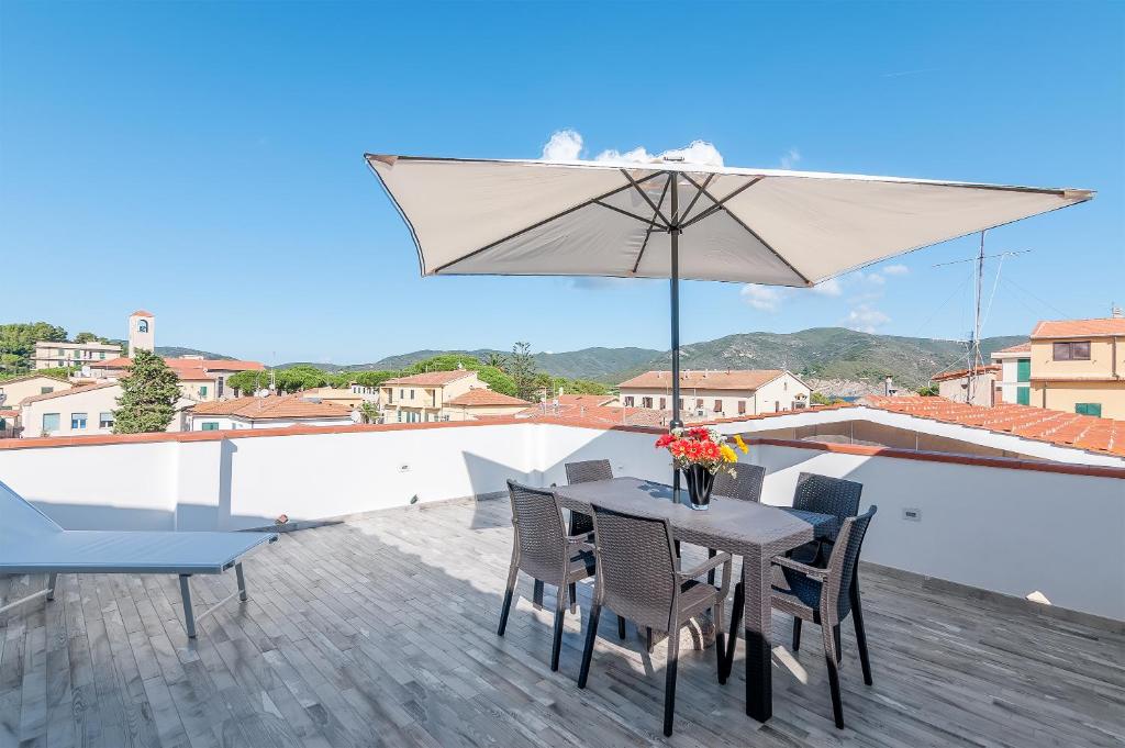 een tafel en stoelen met een parasol op een dak bij Elena in Marina di Campo