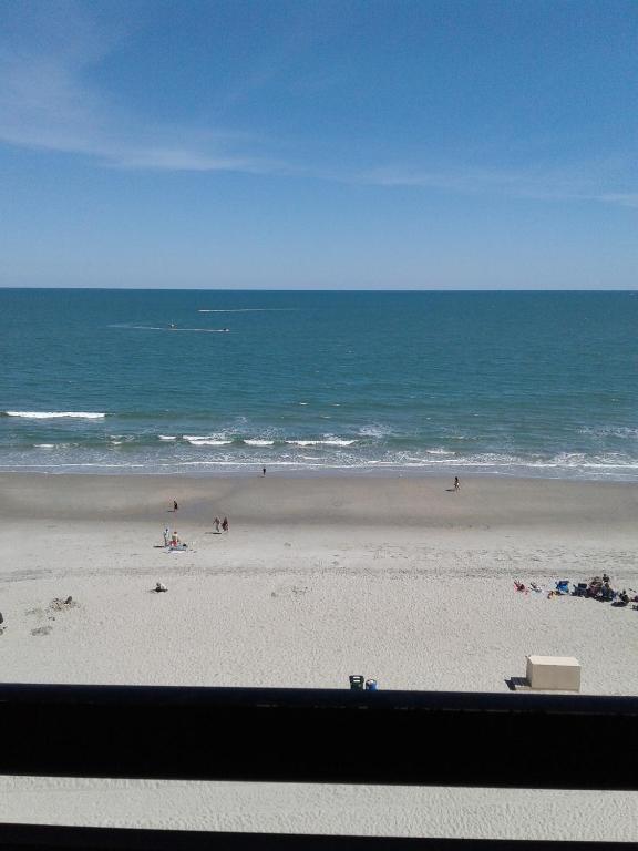 a beach with people on the sand and the ocean at Ocean Front Rentals in Myrtle Beach