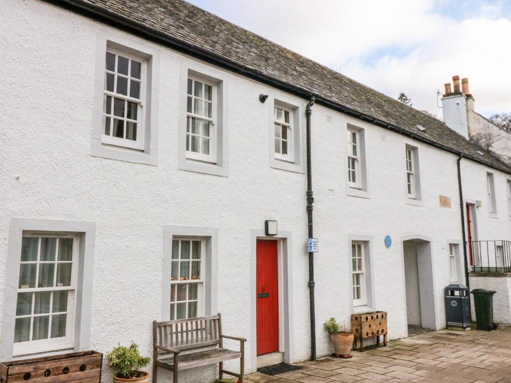 a white house with a red door at 1 The Cross in Dunkeld