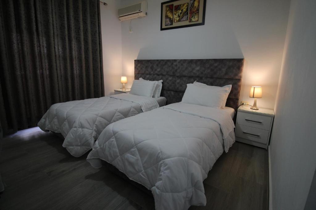 two beds in a hotel room with white sheets at Julia Hotel in Sarandë
