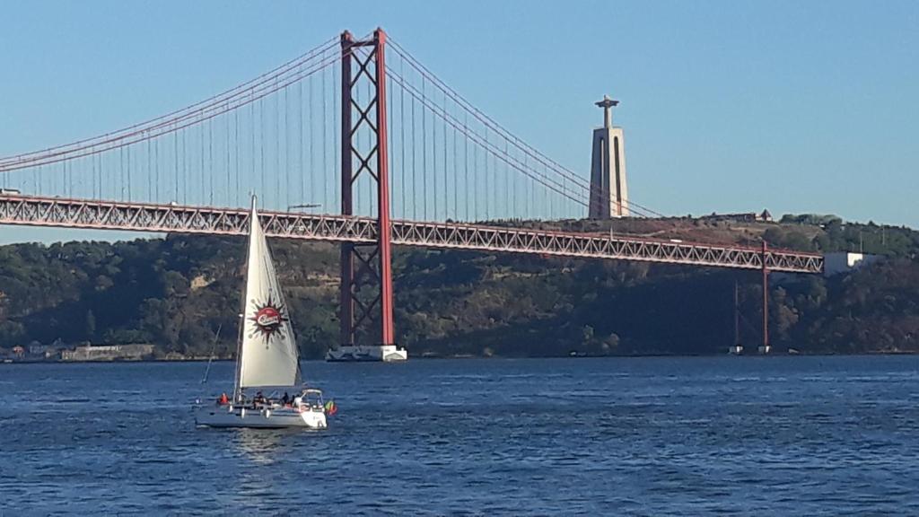 a sailboat in the water in front of a bridge at Ameli Rooms in Lisbon