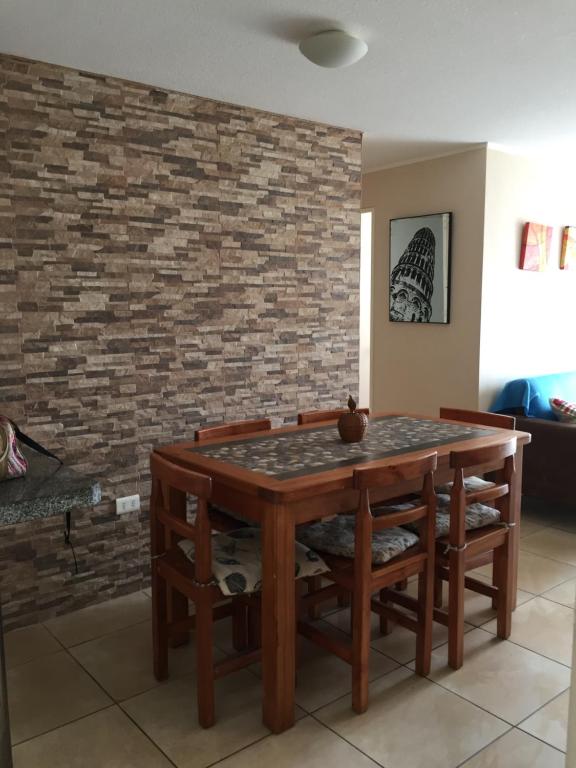 mesa de comedor y sillas contra una pared de ladrillo en Acogedor departamento cerca del mar, en La Serena