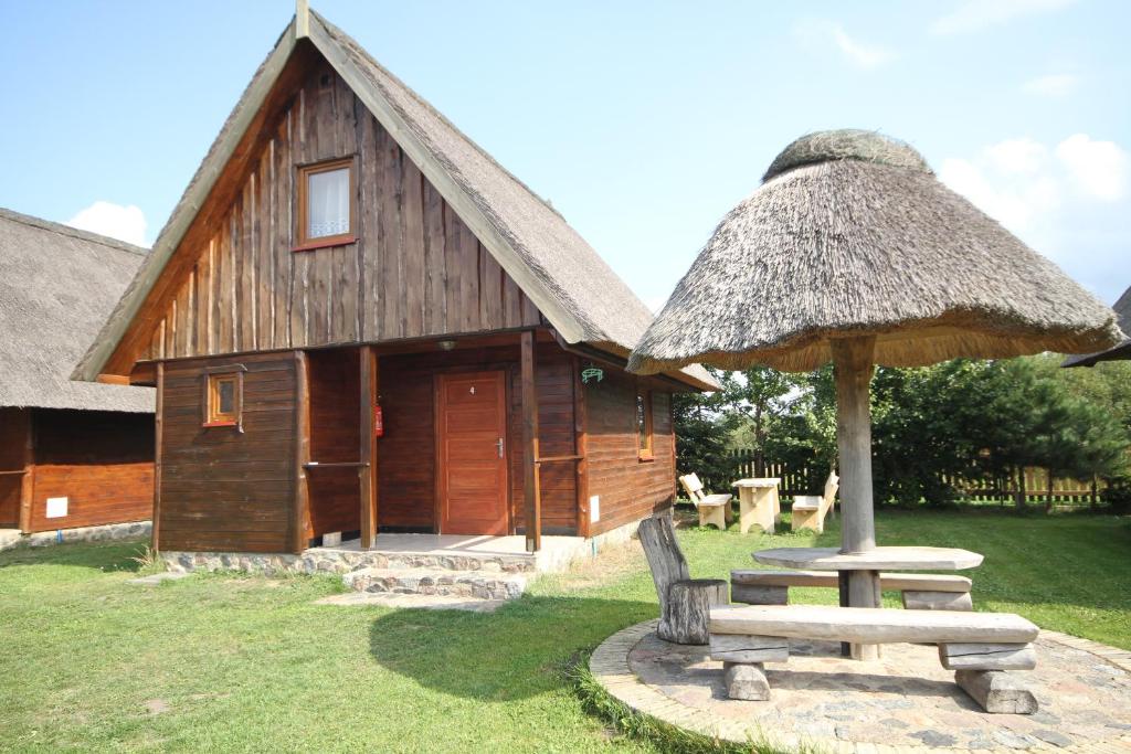 een hut met een picknicktafel en een paraplu bij Domki Ranczo Itrich in Łeba