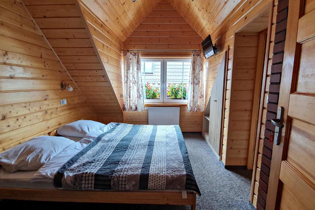 a bedroom with a bed in a wooden house at Agroturystyka u Jarka in Bryzgiel