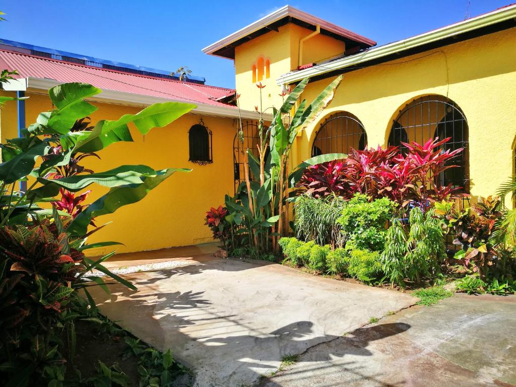 Una casa amarilla con plantas delante. en Hotel Casa 69, en San José