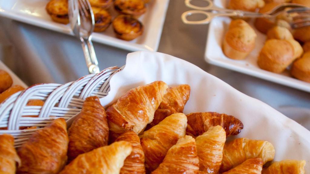 a white plate with a basket of croissants on a table at InterContinental Porto - Palacio das Cardosas by IHG in Porto