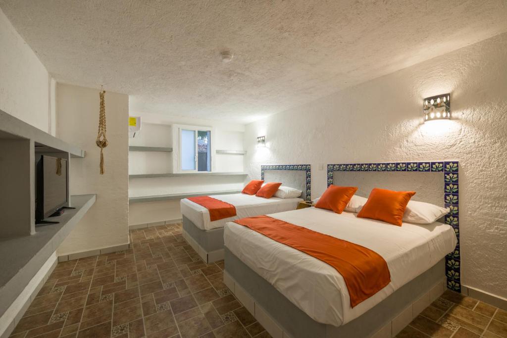 a bedroom with two beds with orange pillows at Hotel Caracol Puerto Morelos in Puerto Morelos