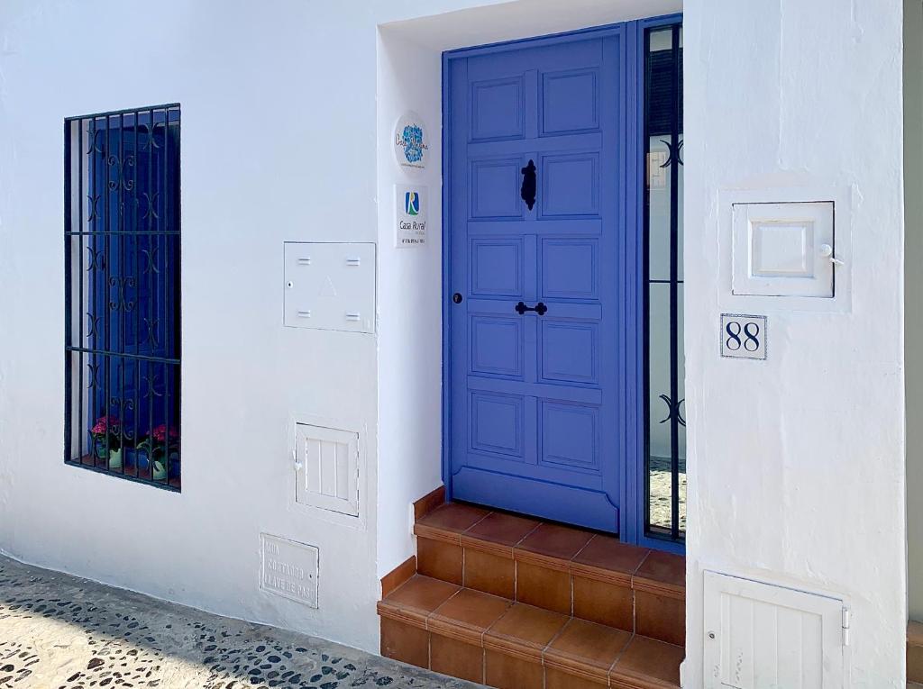a blue door on a white wall with stairs at Casa Marina in Frigiliana
