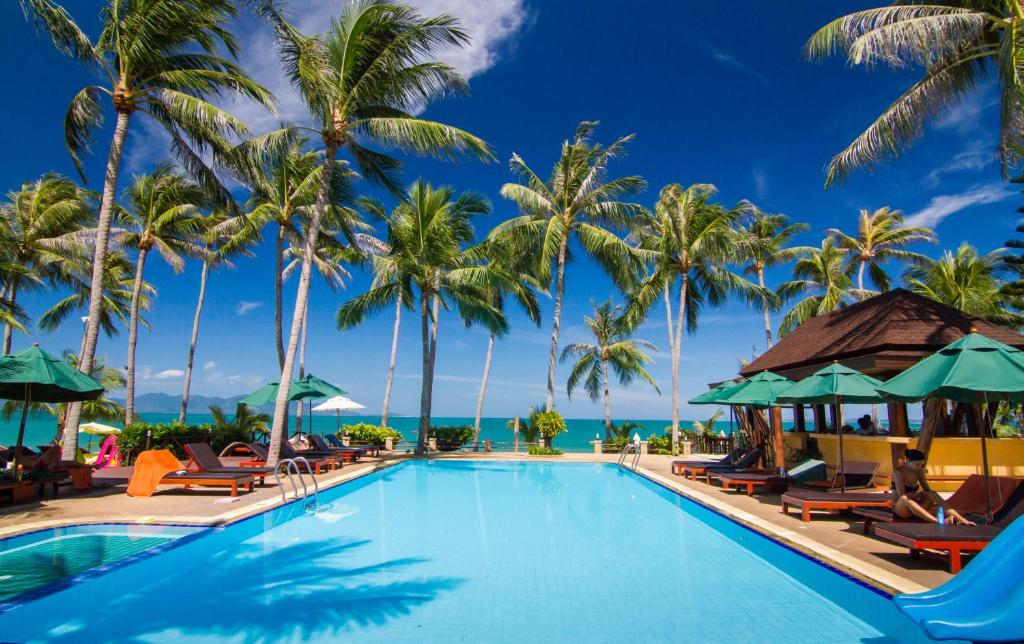 una piscina con palmeras y sillas en Coco Palm Beach Resort - SHA Extra Plus en Mae Nam