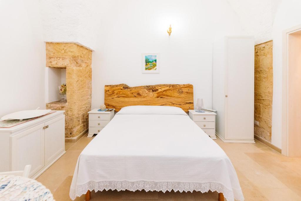 una camera con letto bianco e testiera in legno di Iolanda Vacanze a Lucugnano