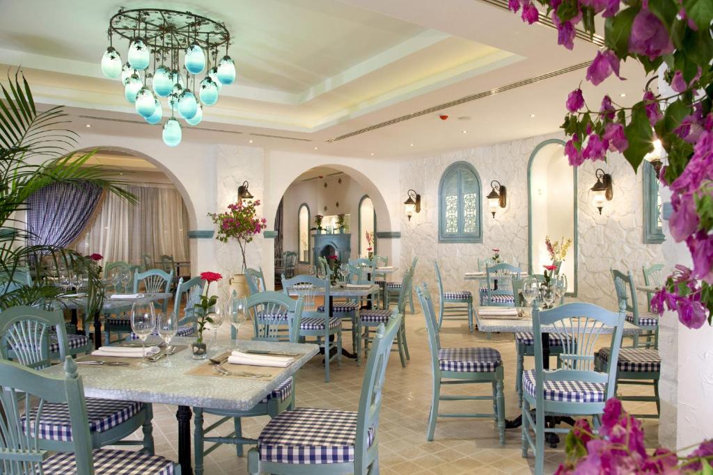 a restaurant with tables and chairs and a chandelier at Sunrise Arabian Beach Resort in Sharm El Sheikh