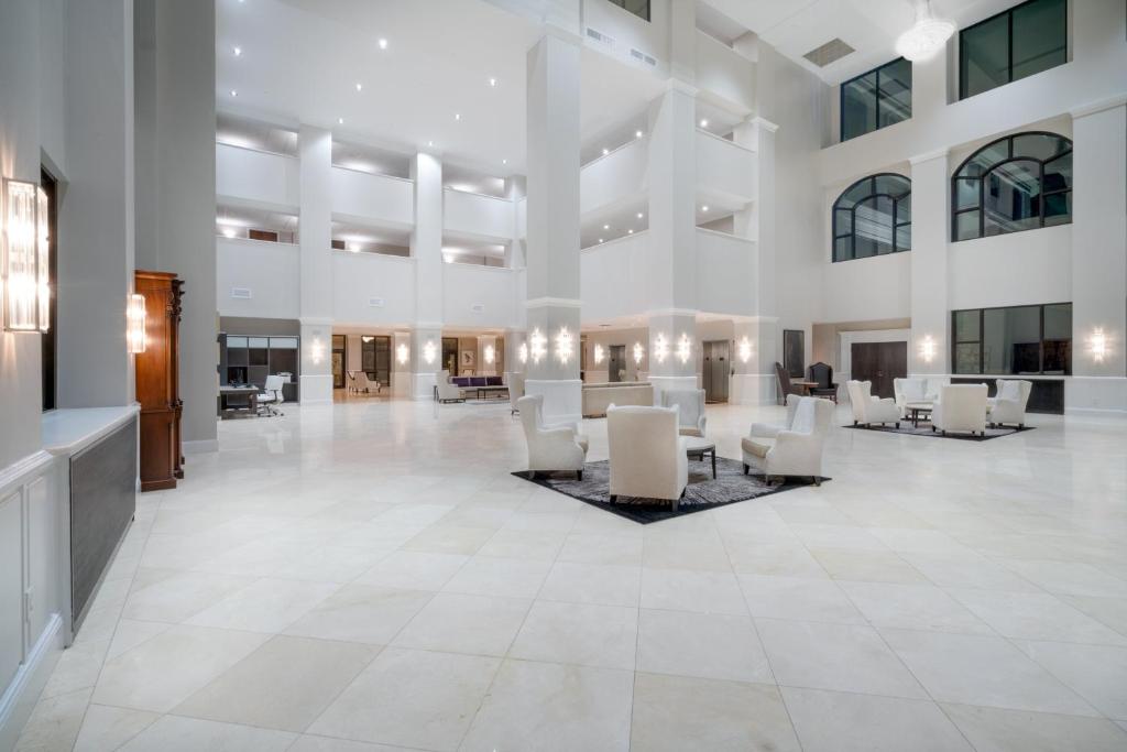 um grande átrio com cadeiras e mesas brancas em Holiday Inn Wilmington by IHG em Gurneyville