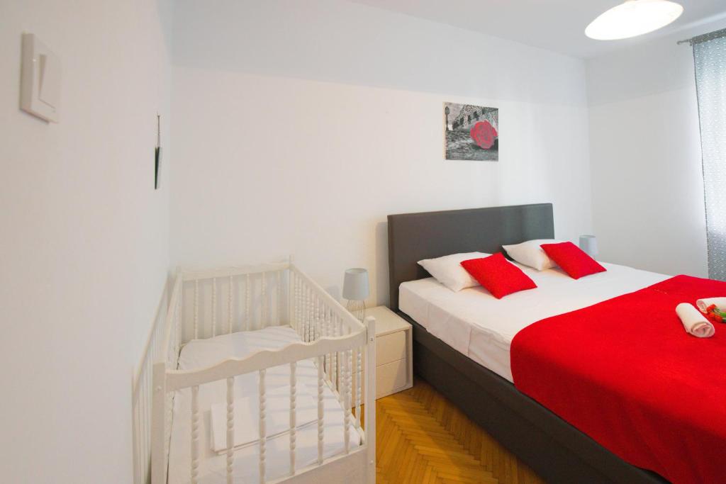 a bedroom with a bed and a crib with red pillows at Ana Guesthouse in Dubrovnik