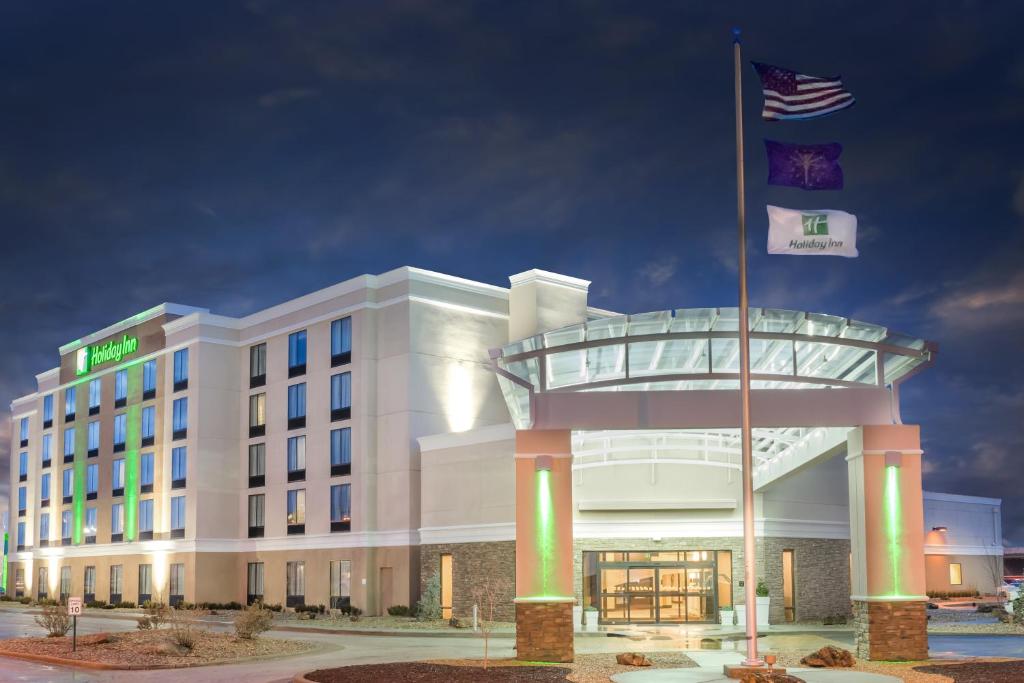 Holiday Inn - Terre Haute, an IHG Hotel في تير هوت: مبنى الفندق مع وجود علامتين أمامه