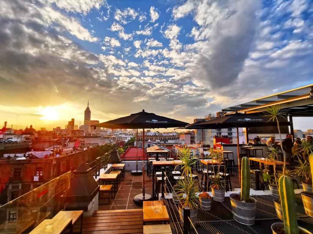 eine Dachterrasse mit Tischen und Sonnenschirmen auf einem Gebäude in der Unterkunft Hostel Mundo Joven Catedral in Mexiko-Stadt