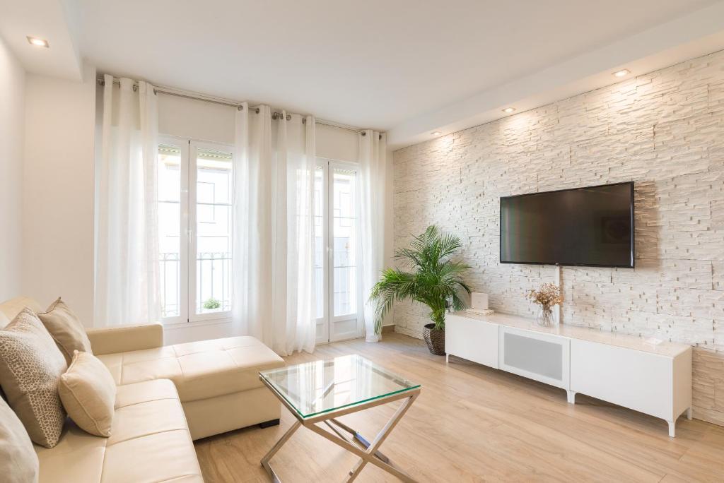 a living room with a couch and a tv on a brick wall at Agua III & balconies by ELE Apartments in Málaga