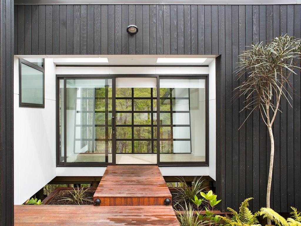 a house with a window and a wooden table at The Treehouse - Kaiteriteri Holiday Home in Kaiteriteri