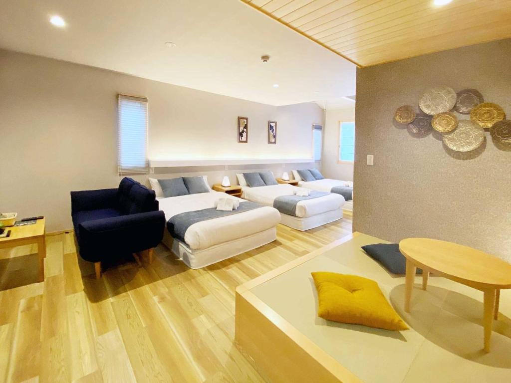 um quarto com duas camas, um sofá e uma mesa em HOTEL CLA-SS HIROSHIMA-OZU em Hiroshima