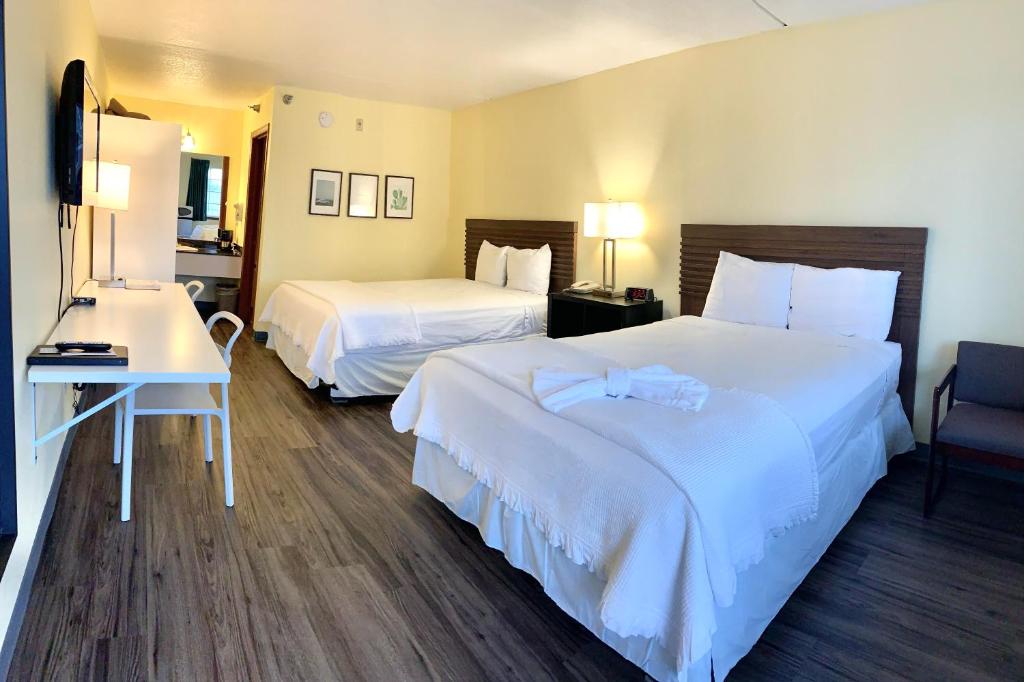 a hotel room with two beds and a desk at Seven Gables Inn in Branson