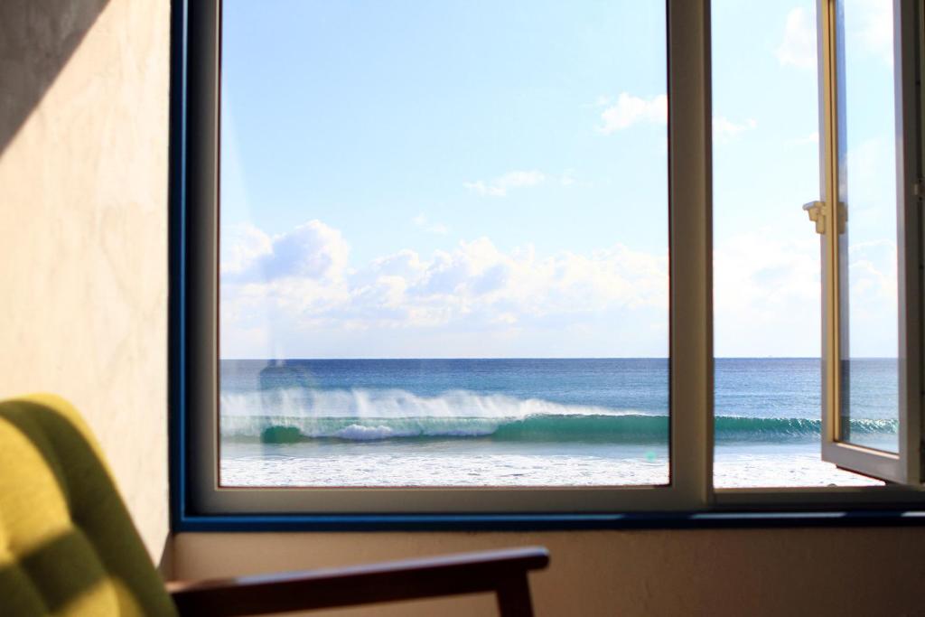 una ventana con vistas al océano desde una habitación de hotel en kODATEL コダテル 函館シーサイド en Hakodate