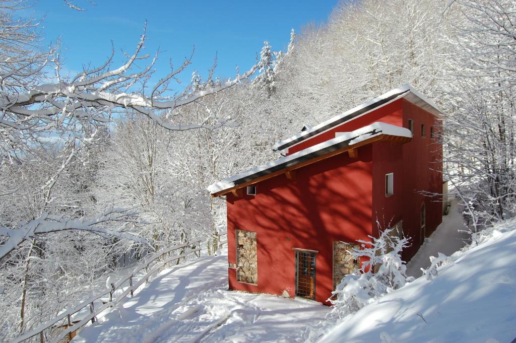 uma cabana vermelha na neve com árvores cobertas de neve em Rifugio Casello Margherita em Camigliatello Silano