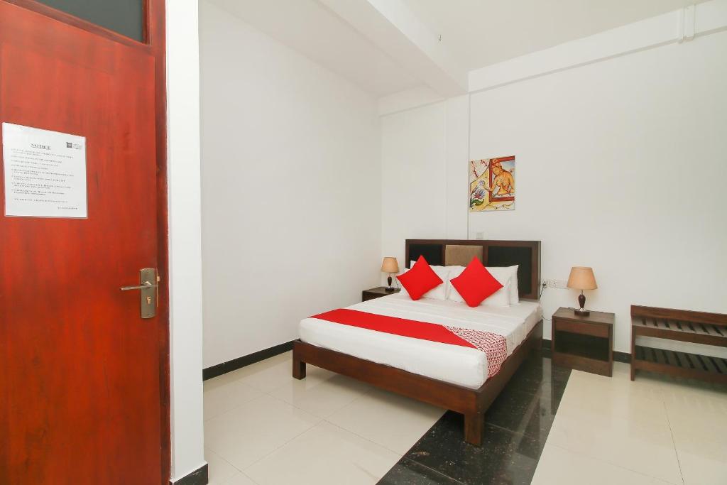 a bedroom with a bed with red pillows and a door at Hotel 198 Negombo in Negombo
