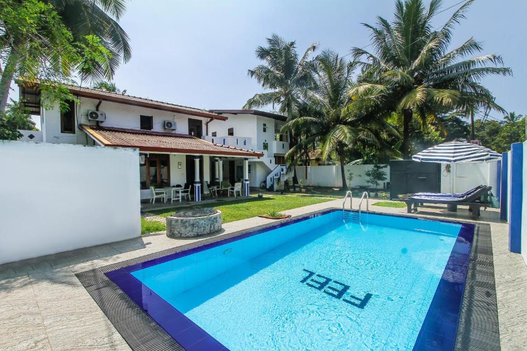 a villa with a swimming pool in front of a house at FEEL Villa in Kalutara