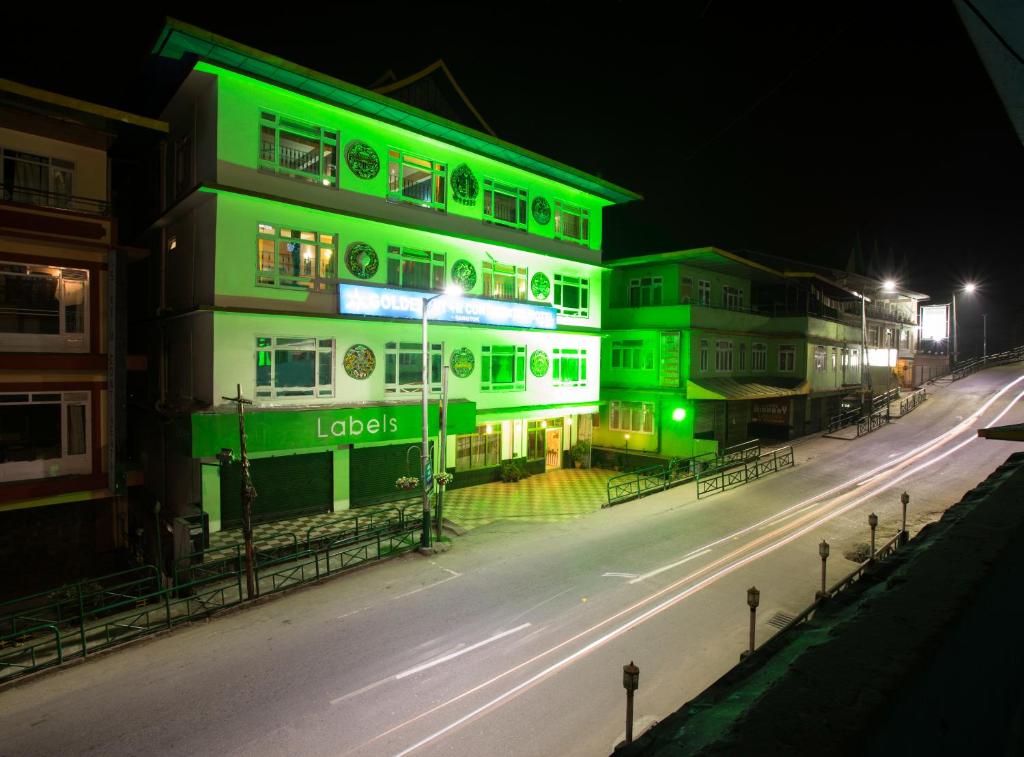 a green and white building on a street at night at Golden Star Continental & Spa in Gangtok